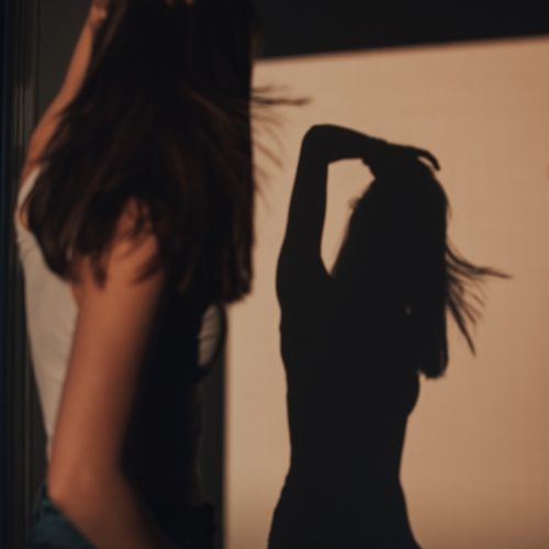 a woman standing in front of her shadow self