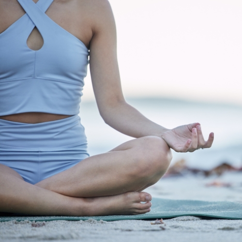 a woman meditating on a beach