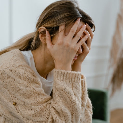 a woman with her head in her hands as she is not in alignment with her human design and is feeling her not-self theme frustration